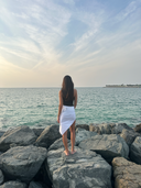 Back view of the Caletta White 100% Cotton Pareo, tied short as a beach skirt. Showcases the versatile rear fit.