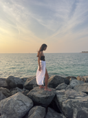 Side view of the Caletta White 100% Cotton Pareo worn long, showcasing the elegant flowing fit for seaside style.